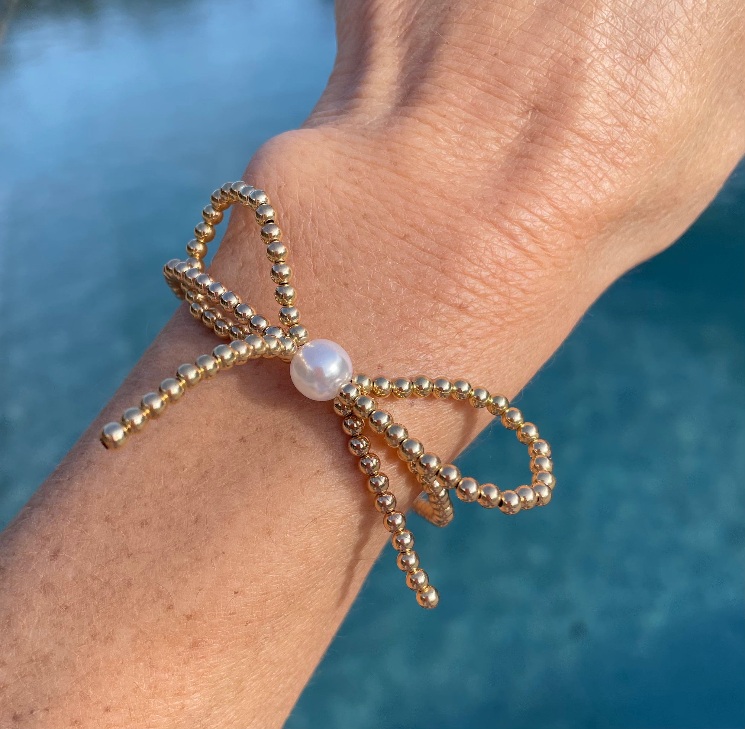 gold beaded bow bracelet with pearl in the middle